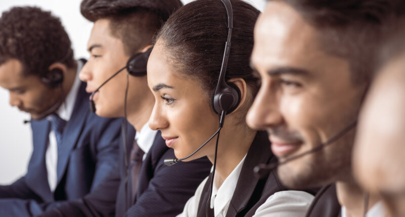 Close-up view of call center operators in headsets working together