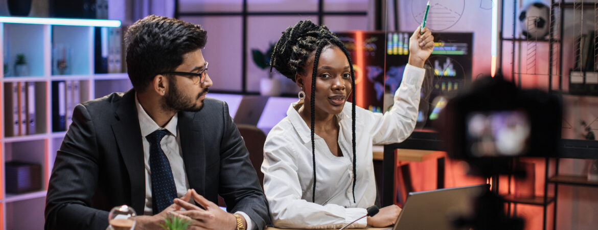 Attractive male and female financiers, arab manager and confident african american business woman explaining online economic charts on glass board to their colleagues sitting in front of video camera.